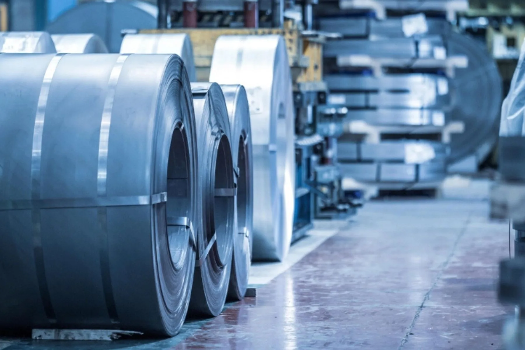 Coils of sheet metal stored beside a production line.